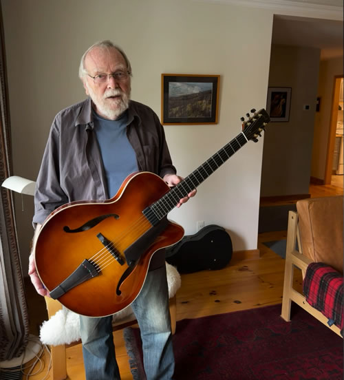 Photo of Oskar holding an archtop guitar